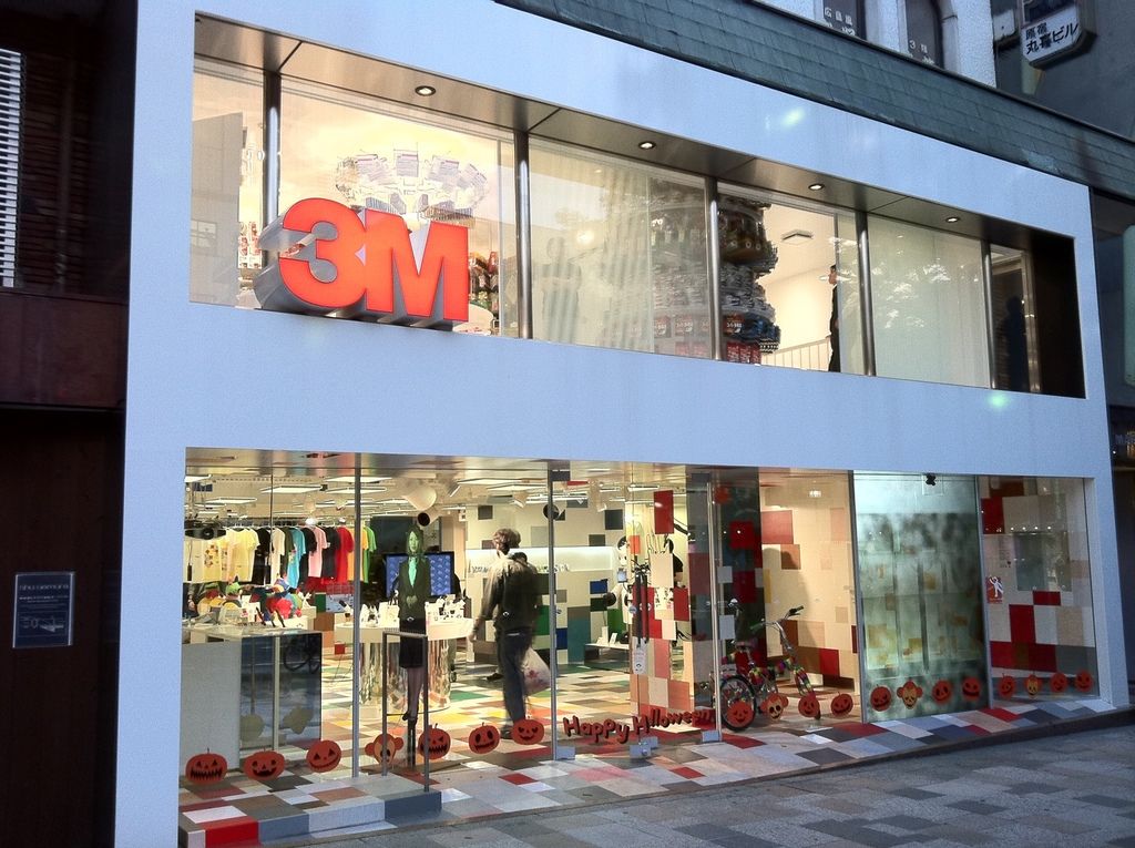 There is a building with a glass wall. Inside the building there are dresses hanged on the hangers....